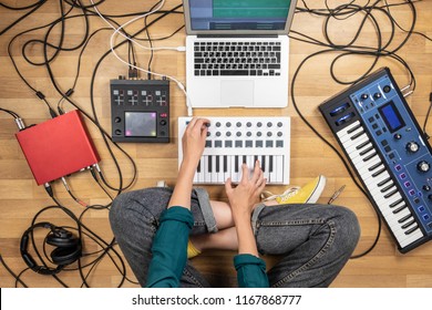 Mulher fazendo música eletrônica no laptop e instrumentos digitais. Vista superior da jovem produzindo música indie moderna em sintetizadores e controladores digitais