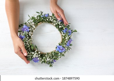 Woman Making Flower Wreath At White Wooden Table, Closeup. Space For Text