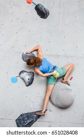 Woman making Free bouldering competition session at Indoor Rock Climbing wall