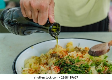 Woman making fresh and delicious potato salad with greens on a tray, pouring olive oil from a bottle into the salad. Turkish cuisine. - Shutterstock ID 2168419627