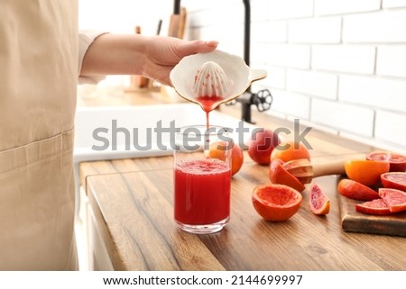 Woman making fresh orange juice in kitchen