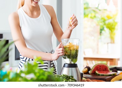 Woman making fruit cocktail in kitchen during cleansing detox diet to boost energy - Powered by Shutterstock