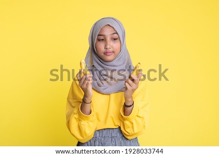 woman making fun with a banana isolated on yellow background.