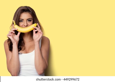 Woman Making Fun With A Banana. Yellow Background