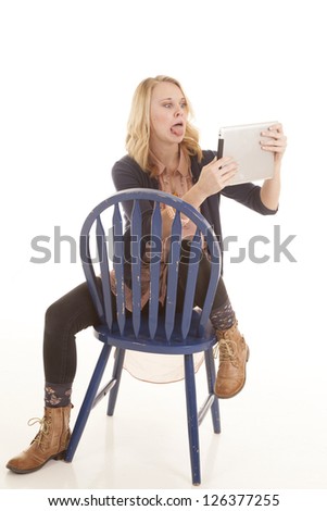 a woman making a funny face on her electronic tablet while sitting in a blue chair.