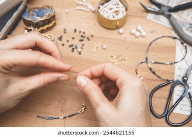 Woman making handmade gemstone jewelry. Beads  and tools on wooden table. Top view with woman hands. - Powered by Shutterstock