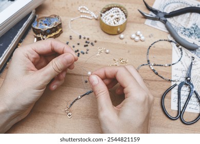 Woman making handmade gemstone jewelry. Beads  and tools on wooden table. Top view with woman hands. - Powered by Shutterstock