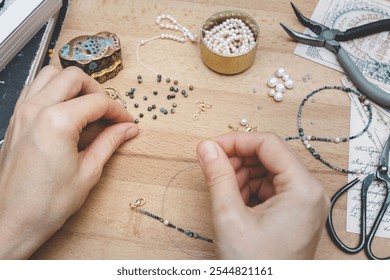 Woman making handmade gemstone jewelry. Beads  and tools on wooden table. Top view with woman hands. - Powered by Shutterstock