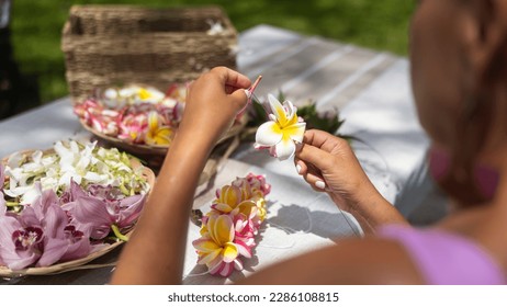 Woman making Hawaiian Lei and Hahu. Process of Handmade flower crown made from Hawaii flower Plumeria.