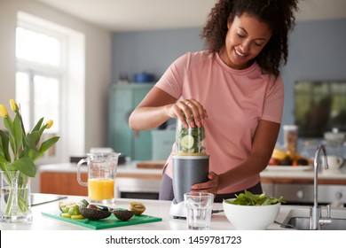 Woman Making Healthy Juice Drink With Fresh Ingredients In Electric Juicer After Exercise