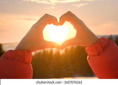 Woman Making Heart With Hands Outdoors At Sunset, Closeup. Winter Vacation