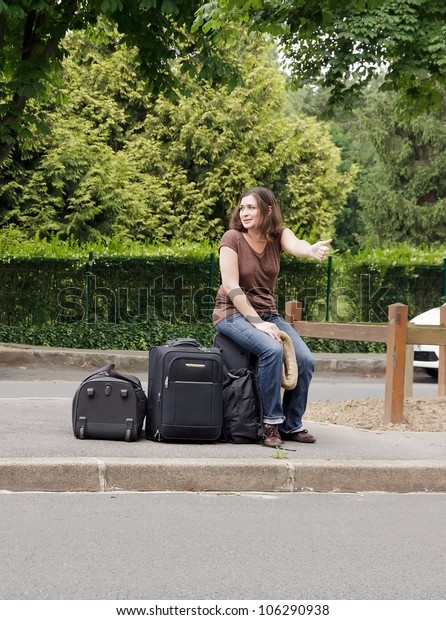 woman making\
hitchhiking, sitting on his\
luggage