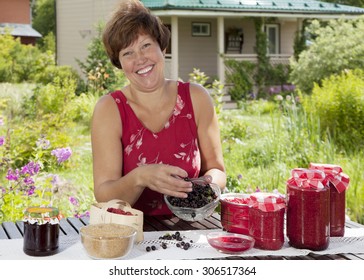 Woman Making Home Made Jam From Berries And Smiling At The Camera 