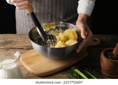 Woman making mashed potato at wooden table, closeup