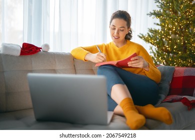 Woman Is Making Notes Sitting On The Sofa In The Living Room Decorated For Christmas.