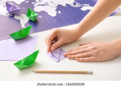 Woman Making Origami Boat At Table