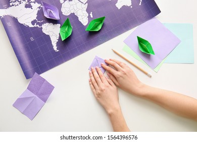 Woman Making Origami Boat At Table