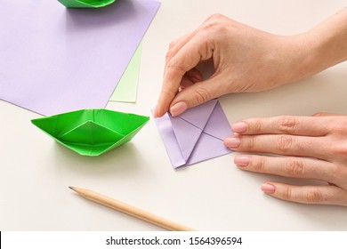 Woman Making Origami Boat At Table