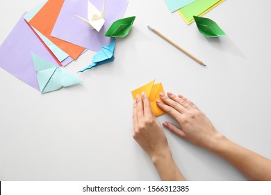 Woman Making Origami Figures At Table