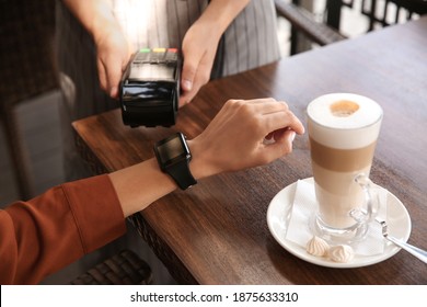 Woman Making Payment With Smart Watch In Cafe, Closeup