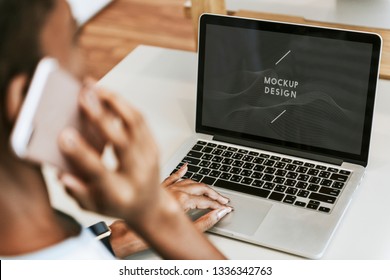 Woman making a phone call while working on her laptop