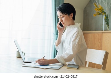 Woman making a phone call while working remotely - Shutterstock ID 2140240817