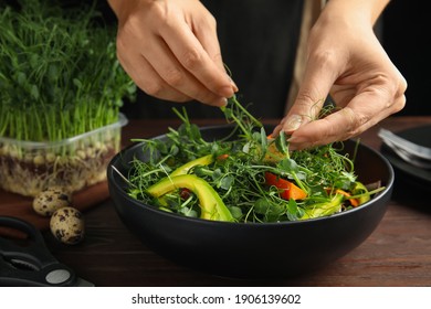 Woman Making Salad With Fresh Organic Microgreen At Wooden Table, Closeup