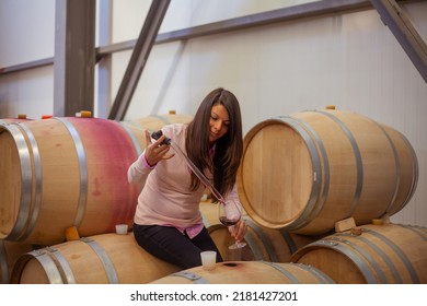 Woman Making A Sample Of Red Wine From Barrel With A Special Tool