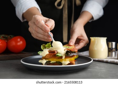 Woman making sandwich with mayonnaise at grey table, closeup