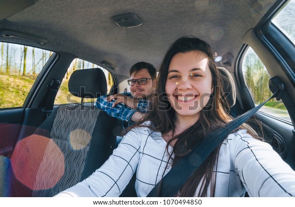 woman making selfie while driving car with\
slipping man on backseats. car travel\
concept