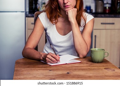 Woman making a shopping list in her kitchen