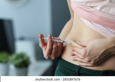 Woman making skin fold on stomach and injecting medicine from syringe at home. Continuous administration of insulin in treatment of type 2 diabetes mellitus concept