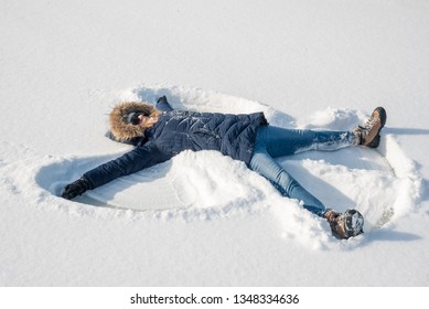 Woman Making A Snow Angel In New Snow Outdoors In Winter