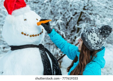 Woman Making Snowman In Winter Day Put Carrot As Nose