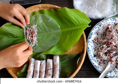 Woman Making Spring Rolls Or Cha Gio At Home, Homemade Food Stuffing From Meat And Wrapper By Rice Paper, Hand Rolling Vietnamese Egg Roll On Green Leaf Background