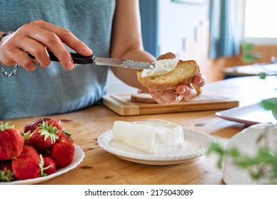 Woman making summer strawberry sandwich. Female hands spread stracchino cheese on bread for toast. Healthy eating, fruit dieting brunch. - Shutterstock ID 2175043089
