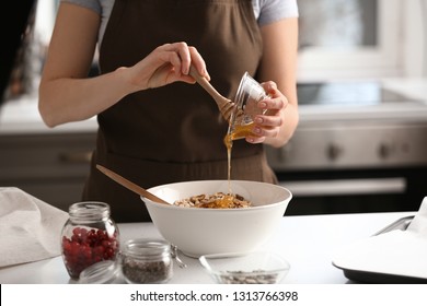 Woman Making Tasty Granola Bars In Kitchen