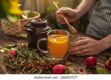 Woman Is Making A Tasty And Healthy Vitamin Tea From Fresh Sea Buckthorn Berries With Honey. Concept Of A Cozy Autumn Atmosphere And Health Care During Colds And Flu Season.