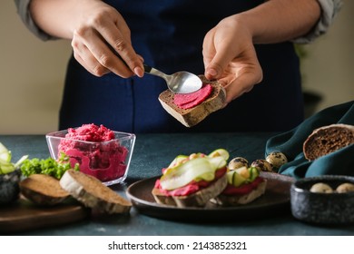 Woman Making Tasty Sandwich With Healthy Hummus At Table