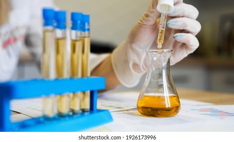 Woman making urine test with ph material in laboratory. Female hands in gloves with pipette and a flask of urine in the medical office