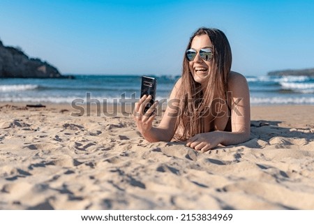 Woman making a video call on the sand on a beach