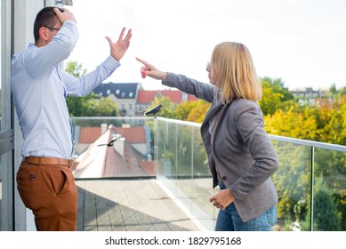 A woman and a man are arguing. Two adult people are arguing on the terrace. People are discussing. Wife and husband on the terrace of the office building. Workers' quarrel. - Powered by Shutterstock