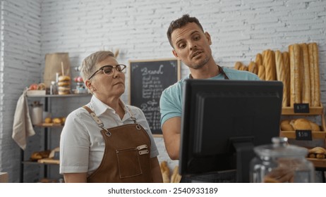 Woman and man, bakery workers, discussing at a computer in a cozy indoor shop with shelves of bread and pastries visible in the background - Powered by Shutterstock