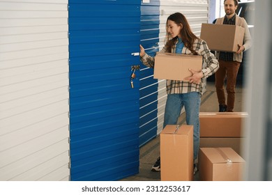 Woman and man with big cardboard boxes into warehouse with self storage unit - Shutterstock ID 2312253617