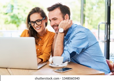 Woman and man at cafe using laptop. Couple spending time at cafeteria browsing internet on computer - Powered by Shutterstock