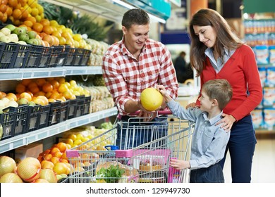 woman with man and child choosing melon fruit during shopping at vegetable supermarket - Powered by Shutterstock