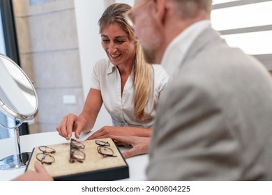 Woman and man choosing eyeglasses from a display at an optical store - Powered by Shutterstock