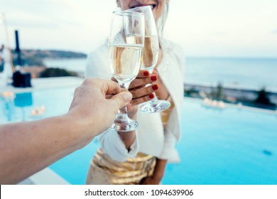 Woman and man clinking glasses at elegant pool party in summer - Powered by Shutterstock