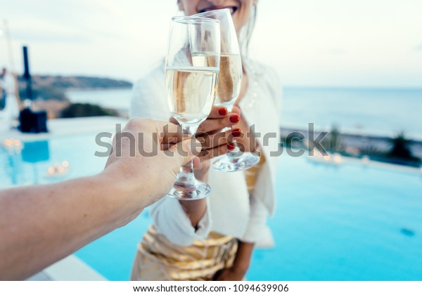 Woman and man clinking glasses at elegant pool\
party in summer