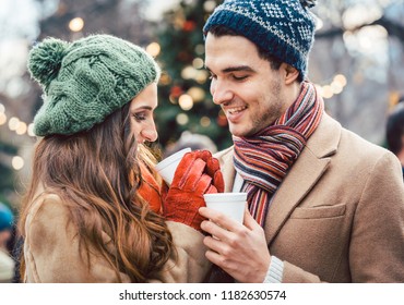 Woman and man drinking mulled wine on Christmas Market in front of tree - Powered by Shutterstock